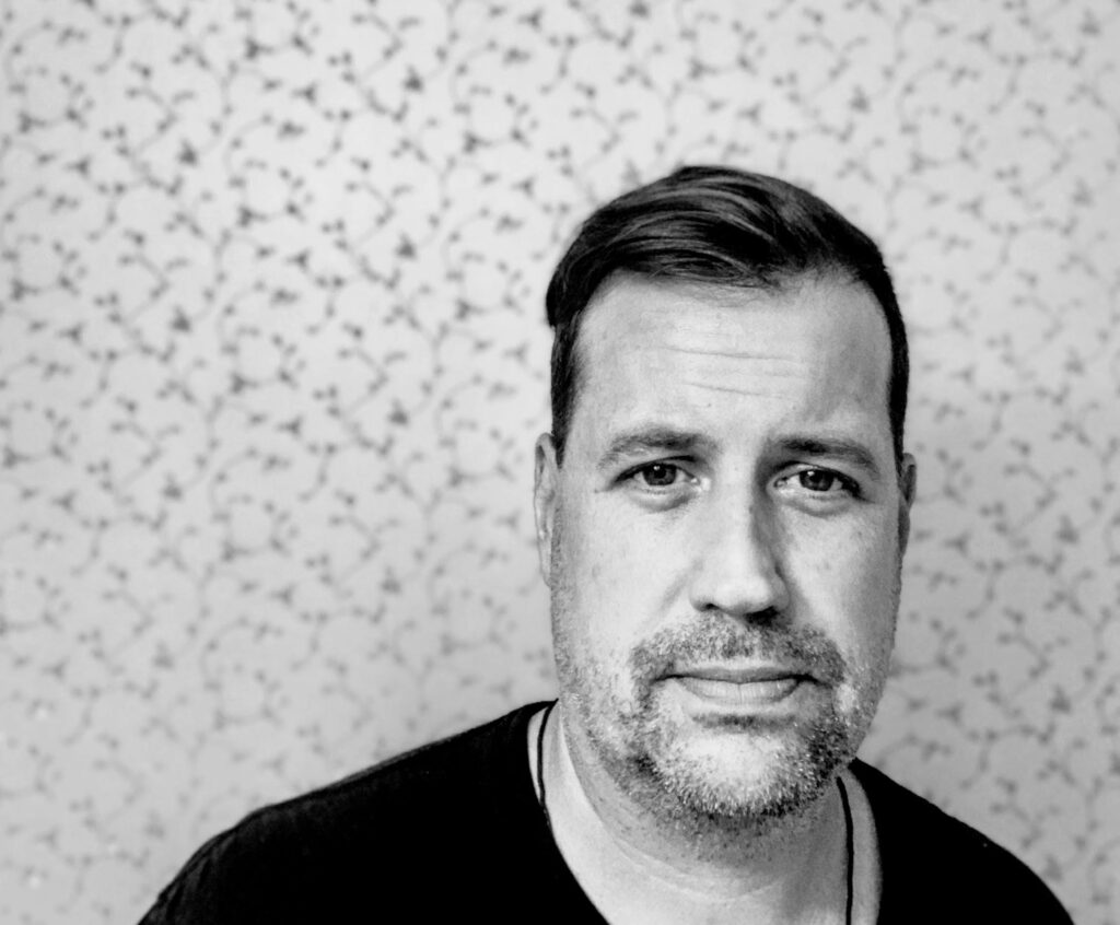 A black and white portrait headshot of Tobias Peterson